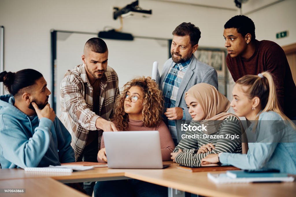 University teacher and his students using laptop during a class in the classroom.